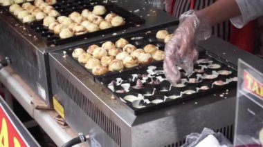 Endonezyalı takoyaki sokak satıcısı sokakta müşteri siparişi hazırlıyor. Takoyaki 'yi hazırlayan satıcıların ellerini kapat..