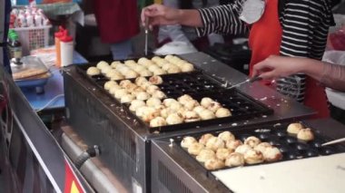 Endonezyalı takoyaki sokak satıcısı sokakta müşteri siparişi hazırlıyor. Takoyaki 'yi hazırlayan satıcıların ellerini kapat..