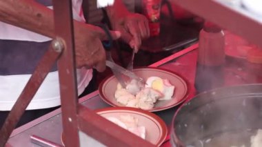 Endonezyalı bir sokak yiyecek satıcısı açık hava pazarında bir müşteriye hizmet veriyor. Malang caddesinde müşteriye 