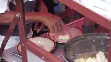 Endonezyalı bir sokak yiyecek satıcısı açık hava pazarında bir müşteriye hizmet veriyor. Malang caddesinde müşteriye 