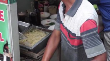 Tavuklu erişte hazırlıyorum. Penjual mie ayam ya da tavuklu erişte satıcısı alıcı için tavuklu erişte yapıyor..
