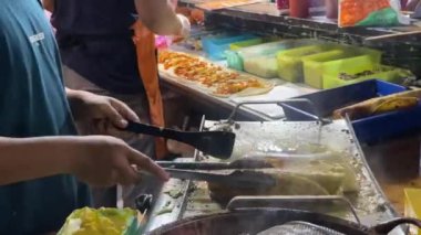 Endonezyalı sokak yemekleri şefi Türk kebabı hazırlıyor. Kısmi görüntüler aşçıyı işyerinde meşgul ederken yakalıyor, ve etrafındaki atmosfer bir pazar etkinliğinde devam eden akşamı yansıtıyor..