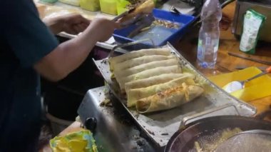 Endonezyalı sokak yemekleri şefi Türk kebabı hazırlıyor. Kısmi görüntüler aşçıyı işyerinde meşgul ederken yakalıyor, ve etrafındaki atmosfer bir pazar etkinliğinde devam eden akşamı yansıtıyor..