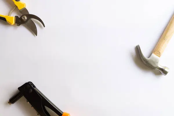 Ahşap saplı metal çekiç, perçin aracı ve budama makası ya da beyaz arka planda çeşitli yerleşimlere sahip bahçe düzenleyicisi.