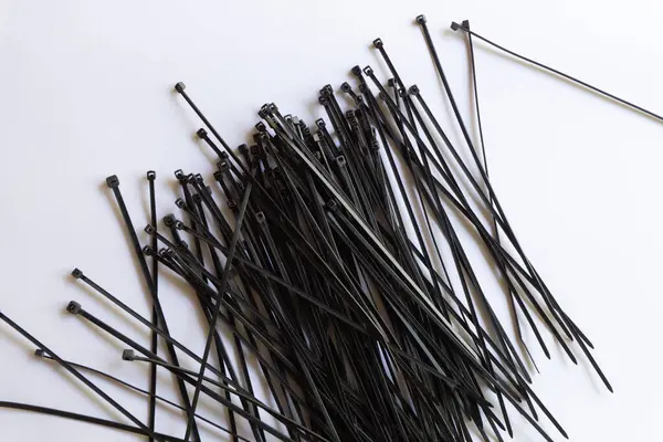 Beyaz arkaplanda izole edilmiş çeşitli yerleşimlere sahip siyah plastik kablo bağlantıları.