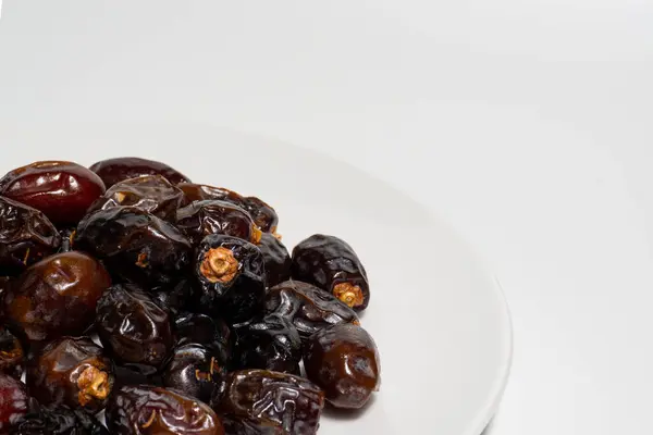 Beyaz arka planda kurumuş tarihler. Birinci kalite meyve tabakta izole edilir. Beyaz arkaplan ile tarih meyvesi.