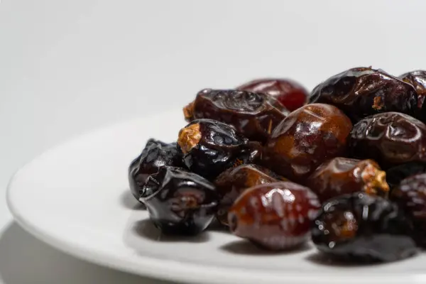 Beyaz arka planda kurumuş tarihler. Birinci kalite meyve tabakta izole edilir. Beyaz arkaplan ile tarih meyvesi.