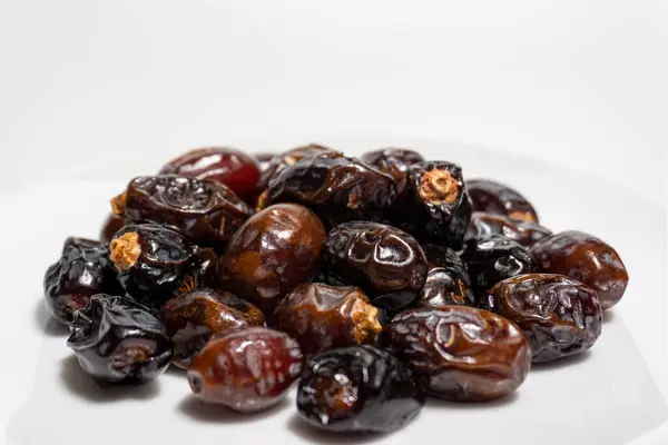 Beyaz arka planda kurumuş tarihler. Birinci kalite meyve tabakta izole edilir. Beyaz arkaplan ile tarih meyvesi.