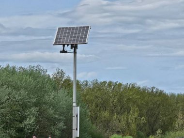 Solarpanel, dass in der Landschaft steht, I 'm Hintergrund Buesche und Baeume