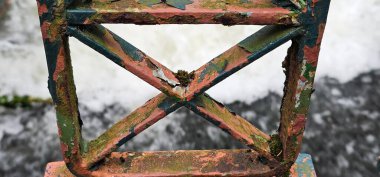 Nehir suyu ve akıntılara bakan paslı demir çitler.