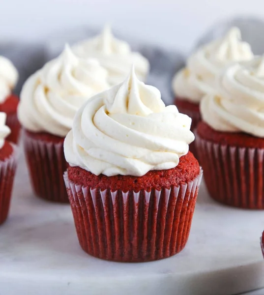 PAKISTAN, KARACHI JANUARY 4,2024 Beautiful delicious red velvet cupcakes with a creamy cream cap on a stone background.