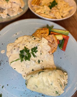 PAKISTAN, KARACHI, JANUARY 9 2024 Spaghetti tavuklu alfredo gri terrazzo masasının üstünde servis ediliyor. Mantarlı, mantarlı tavuk, trüf, zeytinyağı, parmesan peyniri ve İtalyan bitkileriyle servis ediliyor..