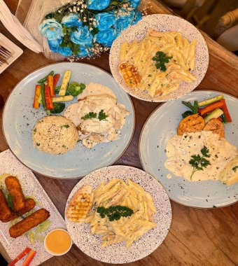 PAKISTAN, KARACHI, HAZİRAN 9. 2024 Tütsülenmiş tavuk peynirli makarna, hallioumi peynirli çubuk, mantar tavuklu pilav ve tarhun.