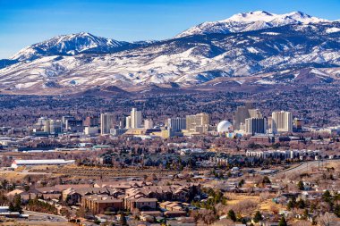 Reno, Nevada ABD - 28 Şubat 2021: Reno Nevada City şehir merkezi, oteller, kumarhaneler ve çevresindeki yerleşim alanlarının karlı dağ geçmişine sahip olduğunu gösteriyor..