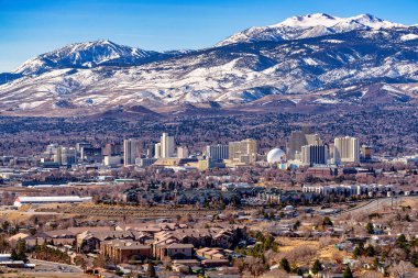 Reno, Nevada ABD - 28 Şubat 2021: Reno Nevada City şehir merkezi, oteller, kumarhaneler ve çevresindeki yerleşim alanlarının karlı dağ geçmişine sahip olduğunu gösteriyor..