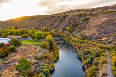 Sonbaharda güzel bir nehrin havadan manzarası. Renkli ağaçlar, çorak çöl dağları ve Reno Nevada yakınlarında parçalı bulutlu bir gökyüzü..