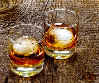 Buzlu ya da buz küreli iki temiz bardak. İçkinin yarısı alkollü, ahşap arka planda..