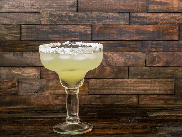 Margarita cocktail in a salt rimmed glass on a rustic wooden background with copy space.