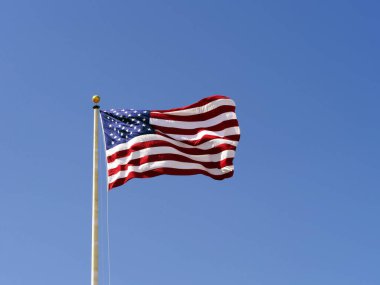 Rüzgarda dalgalanan Amerikan Bayrağı dalgalanan mavi gökyüzüne karşı.