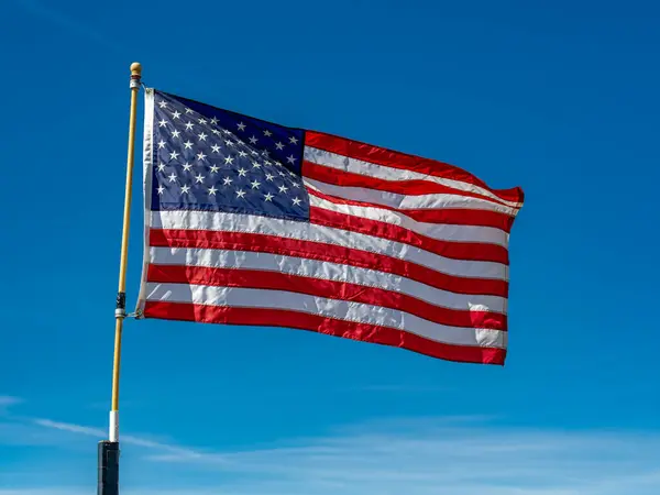 Rüzgarda dalgalanan Amerikan Bayrağı dalgalanan mavi gökyüzüne karşı.