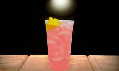 Taze sıkılmış pembe limonata. Temiz bir bardakta buzlu. Ahşap bir masada..