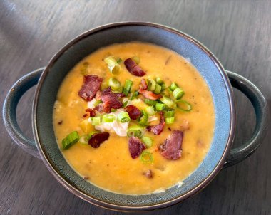 Soğan, soğan, pastırma, ekşi krema ve peynirle süslenmiş Patates Peynir Çorbası.