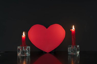Kırmızı kağıt kalp iki mum tarafından aydınlatıldı Sevgililer Günü arkaplanı fotokopi alanı ile.