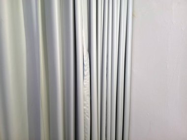 Düzgünce düzenlenmiş perde düz duvarın yanında pürüzsüz metalik gri tonda katlanır.
