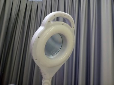 Perdelerin önünde yuvarlak camlı beyaz büyüteç.