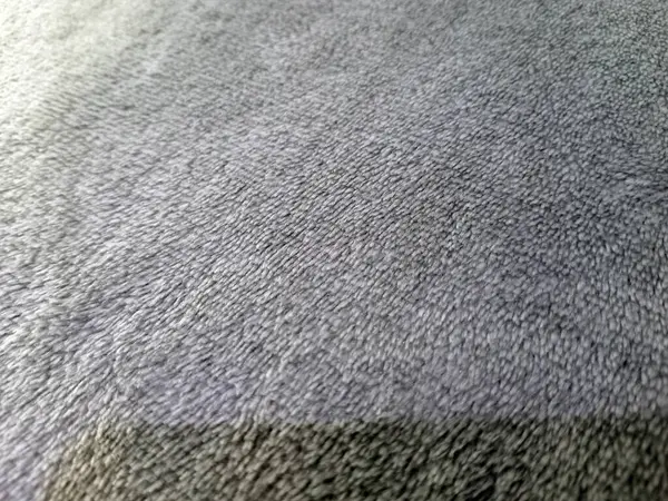 Yumuşak gri kumaş yüzeyinde ince doku ve lifleri gösteren detaylı bir yakın plan.