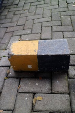 Beton park durdurucu birbirine kenetlenmiş tuğla kaldırıma sarı ve siyaha boyanmış.