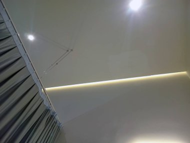 Çağdaş bir iç görünüş, tavana yerleştirilmiş aydınlatma ve gösterişli bir tasarım ile duvarların ve tavanın kesişimini görüntüler, minimalist mimari sergiler.