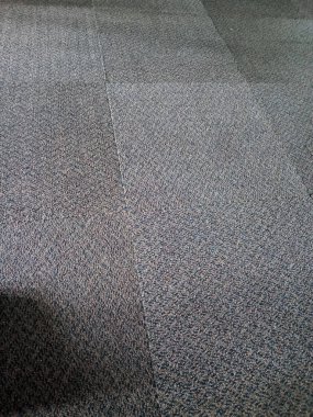 Dokulu halılı zeminin yakın görüntüsü. Kapalı gri tonlarda birbirine kenetlenmiş fayanslar..