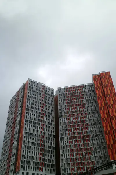 Bulutlu gökyüzüne karşı renkli cepheli uzun modern konut binaları.