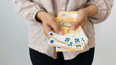 Elinde 50 Euro 'luk para tutan bir kadın. Euro banknotları, Avrupa Birliği kağıt para birimi. Para biriktirme kavramı. Finans, iş, yatırım, enflasyon, satın alma gücü ve sosyal kriz. Tasarruf