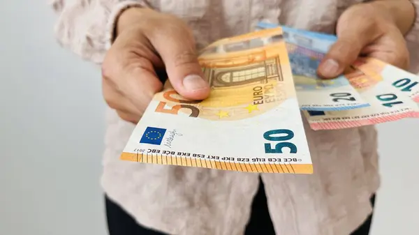 stock image Woman holding euro money. Giving 50 euro notes and holding different bills, euro banknotes, European Union paper currency. Finance, business, investment, inflation, purchasing power and social crisis.