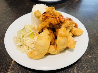 Lezzetli çıtır balık aromalı tavuk tatlı ve ekşi baharatlı börek. İçinde pirinç, taze sebze salatası ve çıtır balık olan bir tabak Çin yemeği..