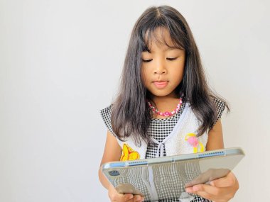 Mobil tablette online öğrenme oyunu oynayan beş yaşındaki tatlı kız arkadaşın kutlu olsun. Mobil tablette çizgi film izliyorum. Asyalı küçük kız evde yatağın üzerine uzanmış tablet izliyor. Alete bağımlı..