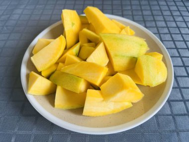 Güneydoğu Asya meyvesi. Tatlı yarım olgun lezzetli mango dilimleri seramik tabakta.
