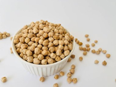 Beyaz arka planda küçük seramik kasede çiğ nohut. Humus pişirmek için geleneksel malzeme. Orta Doğu ve Akdeniz mutfağı. Seçili odaklanma