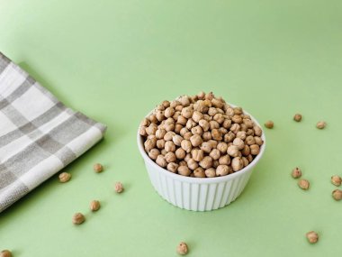 Yeşil arka planda küçük seramik kasede çiğ nohut. Humus pişirmek için geleneksel malzeme. Orta Doğu ve Akdeniz mutfağı. Seçili odaklanma