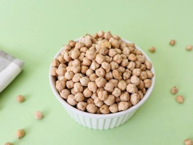 Yeşil arka planda küçük seramik kasede çiğ nohut. Humus pişirmek için geleneksel malzeme. Orta Doğu ve Akdeniz mutfağı. Seçili odaklanma