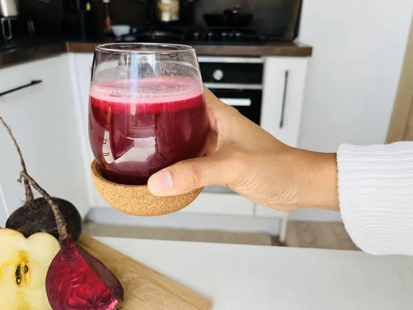 Stock image Woman hand holding a glass of fresh beetroot juice in the kitchen at home. Healthy lifestyle concept