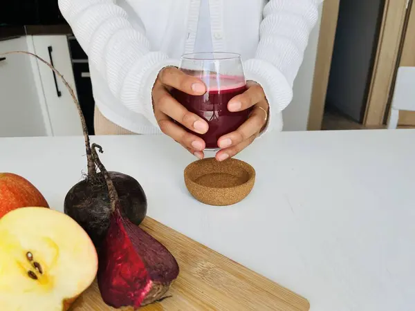 Stock image Unrecognizable woman in white clothes holding a glass of fresh beetroot juice in the kitchen at home. Healthy lifestyle concept