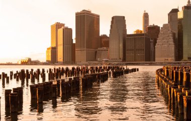 Gün batımında ahşap rıhtımlar ve Manhattan silueti uzakta.