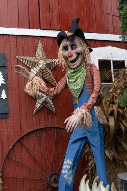 Cadılar Bayramı için giyinmiş kırmızı bir ahırın yanındaki korkuluk.