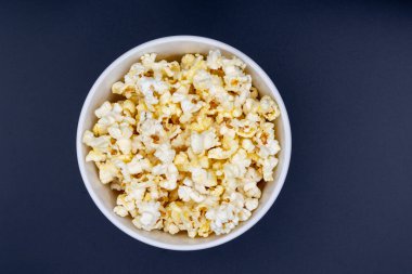 Siyah arka planda beyaz kase mikrodalga patlamış mısır.