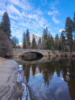 Yarı kubbe ve taştan bir köprü Merced Nehri 'ne yansıyor