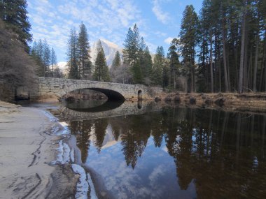 Yarı kubbe ve taştan bir köprü Merced Nehri 'ne yansıyor