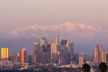 Gün batımında karla kaplı dağlarla kaplı Los Angeles silueti